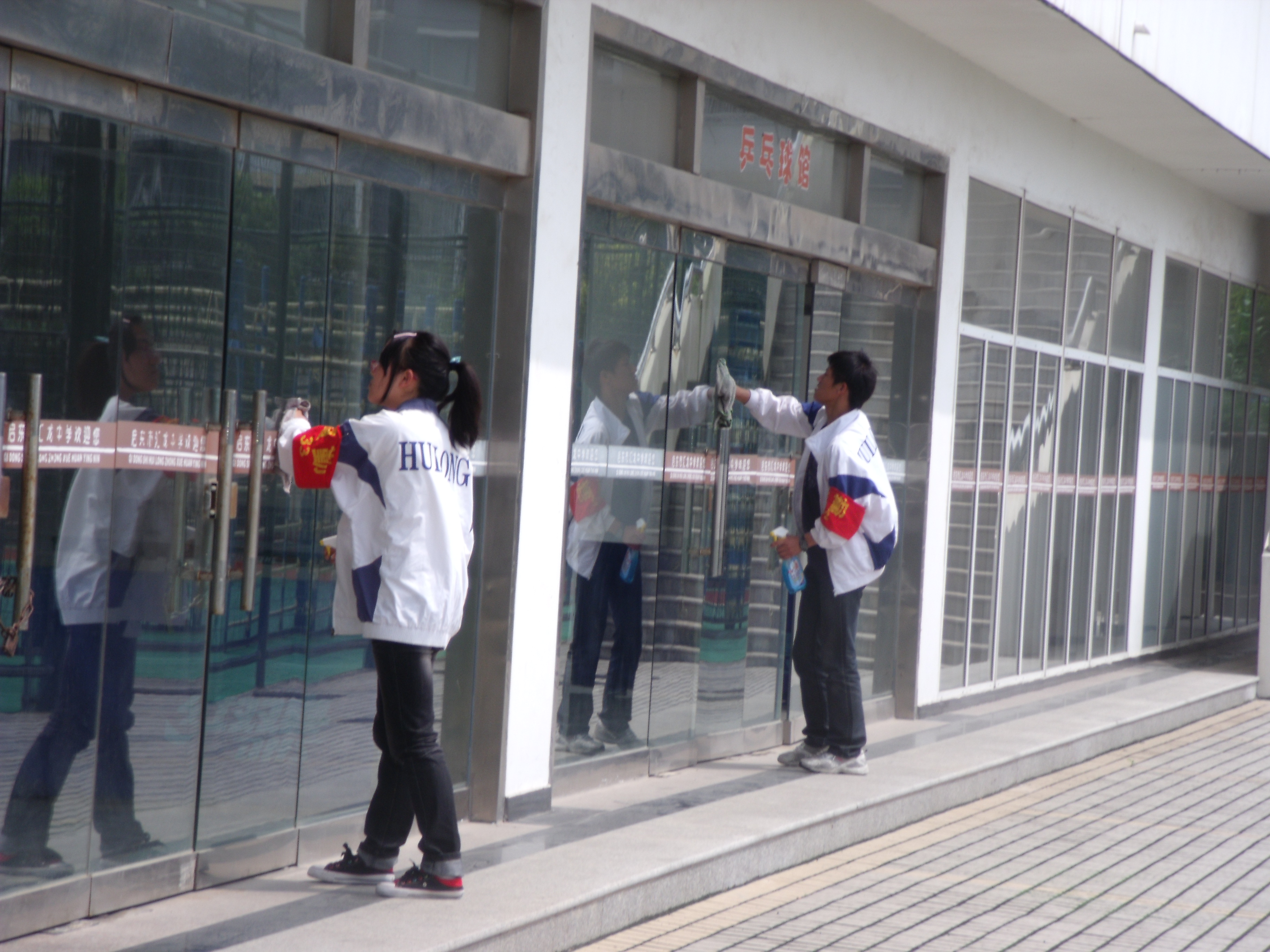 图为原高二16班2名同学认真擦拭体育馆玻璃的场景